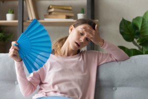 Girl overheating in living room where AC maintenance is required